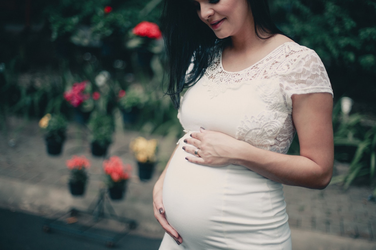 close-up-photo-of-pregnant-woman-in-white-dress-holding-her-2100341.jpg