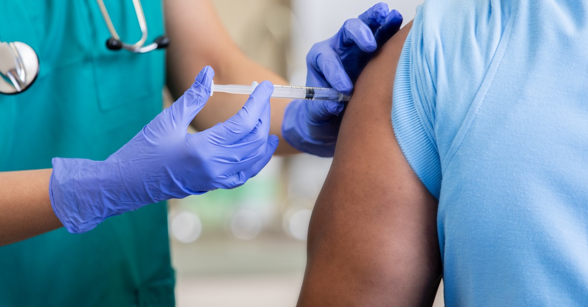 Nurse gives mature African American man a vaccination in doctor's office during coronavirus pandemic