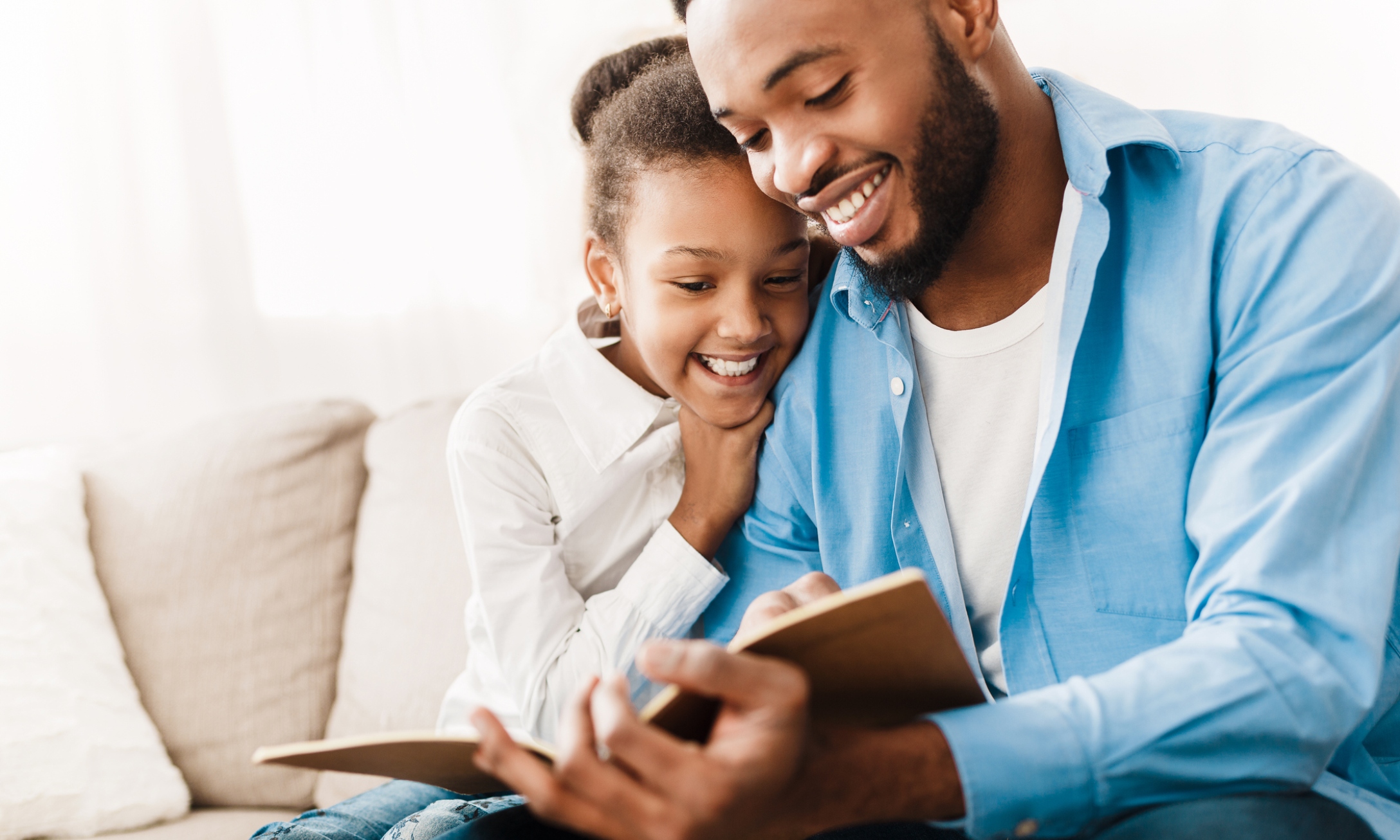 African-american girl and father enjoying reading book together