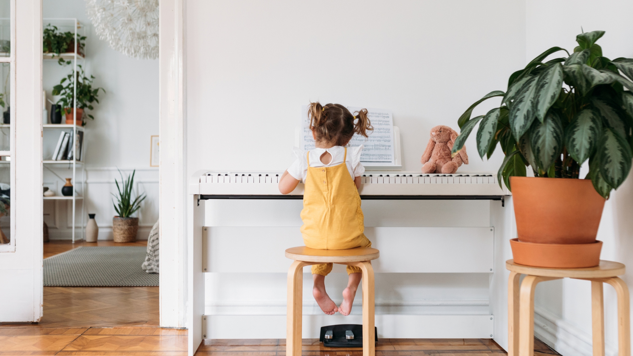 Back view of cute little girl with pigtailes playing a piano.