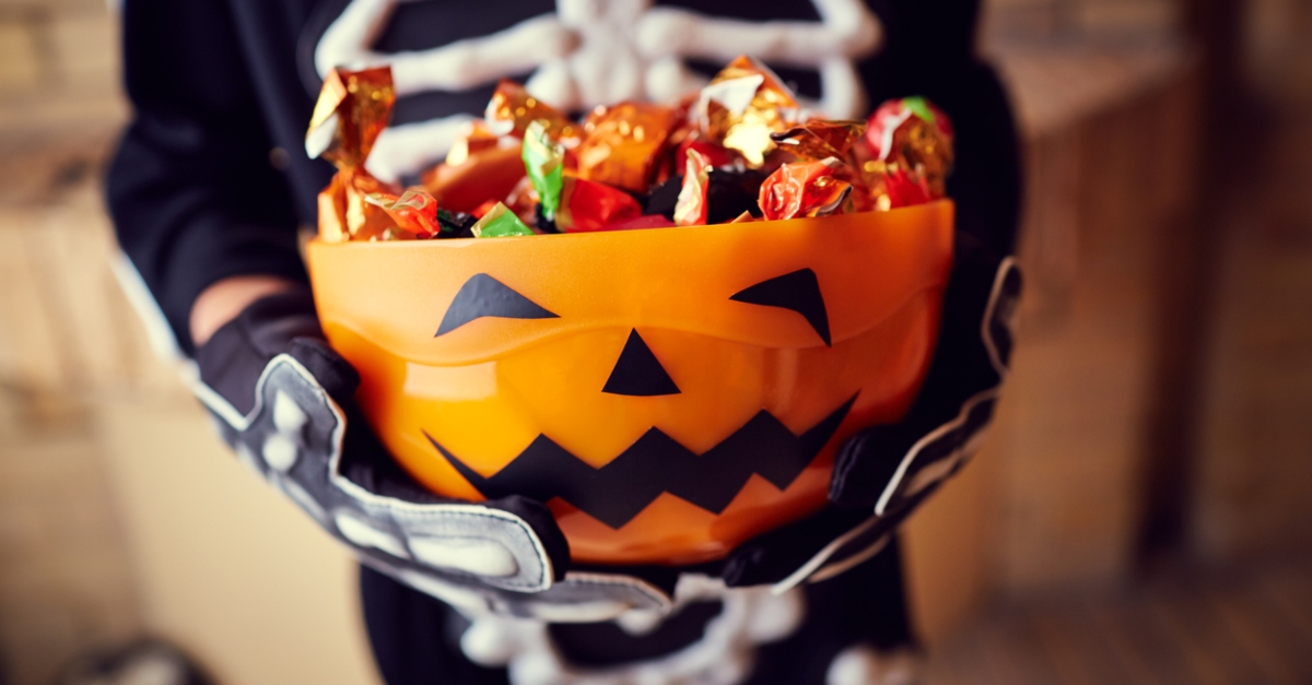 Boy in skeleton costume holding bowl full of candies