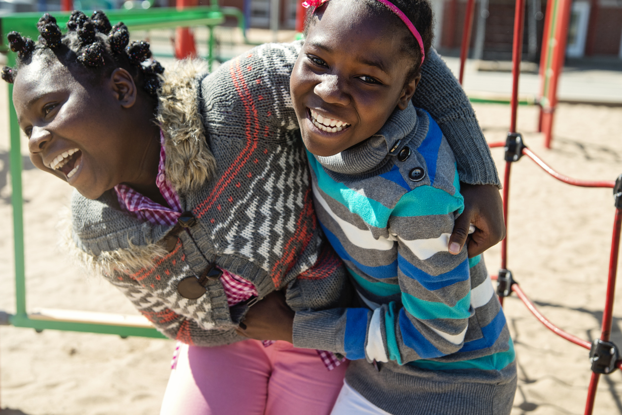 Two african-american twin girls playing in school playground at recess..