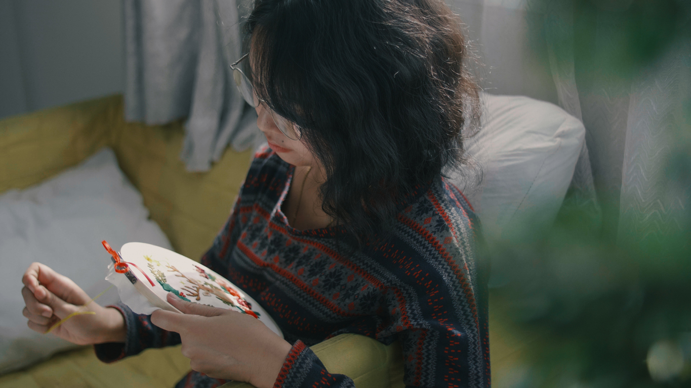 Young woman enjoying cross-stitch for Christmas in home.