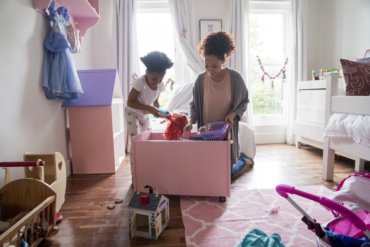 Mother and daughter picking up toys from container