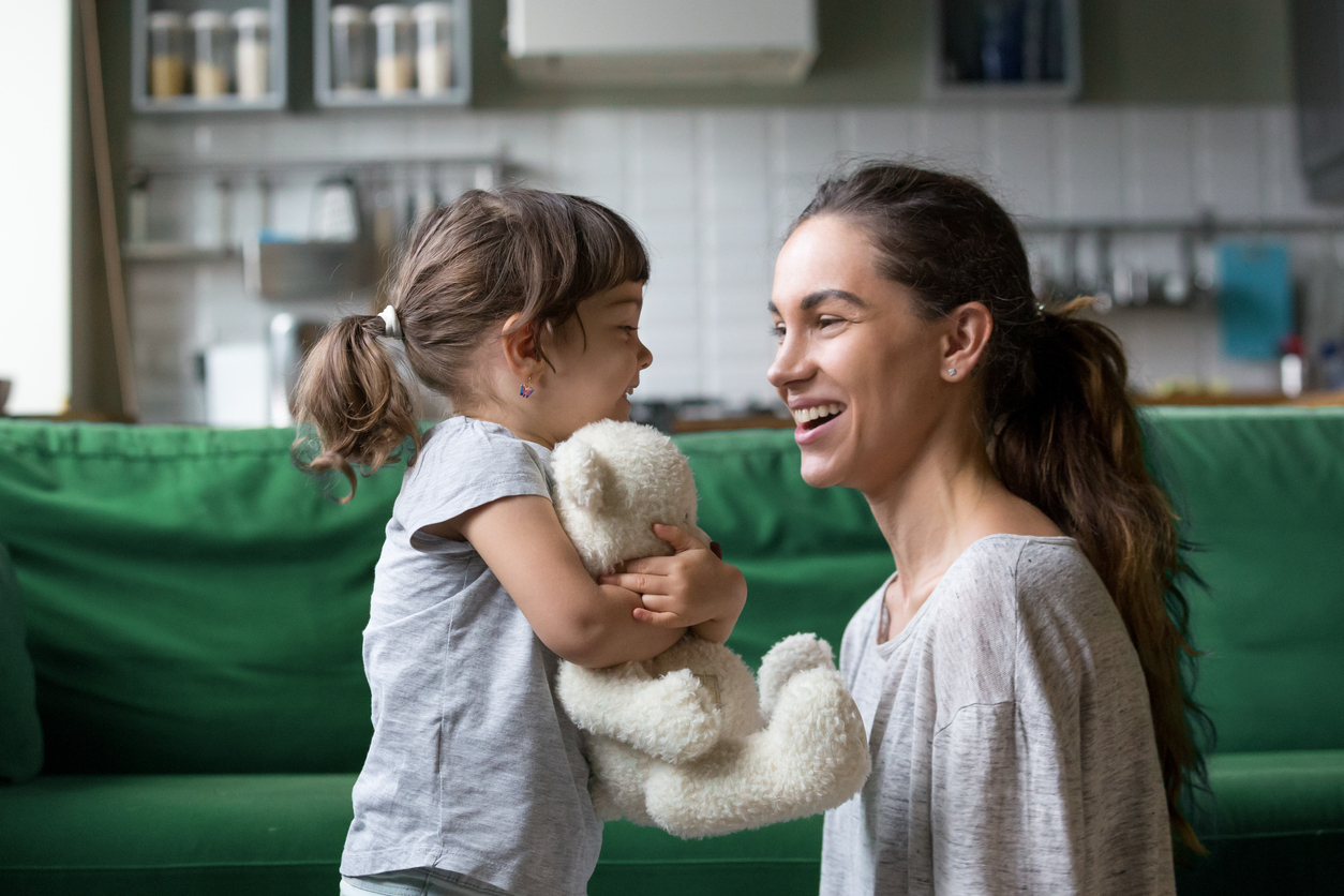 Smiling young mum talking with little daughter