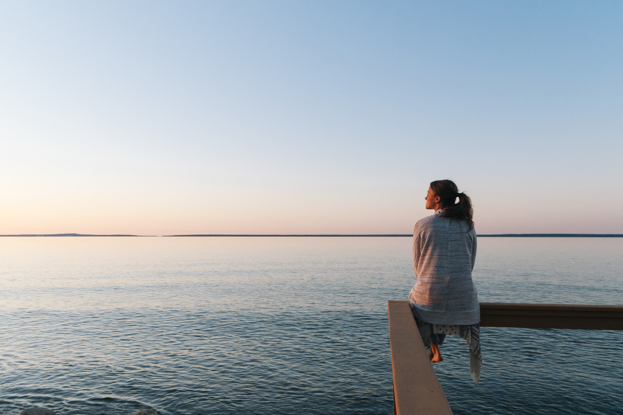 Young woman sitting on edge looks out at view