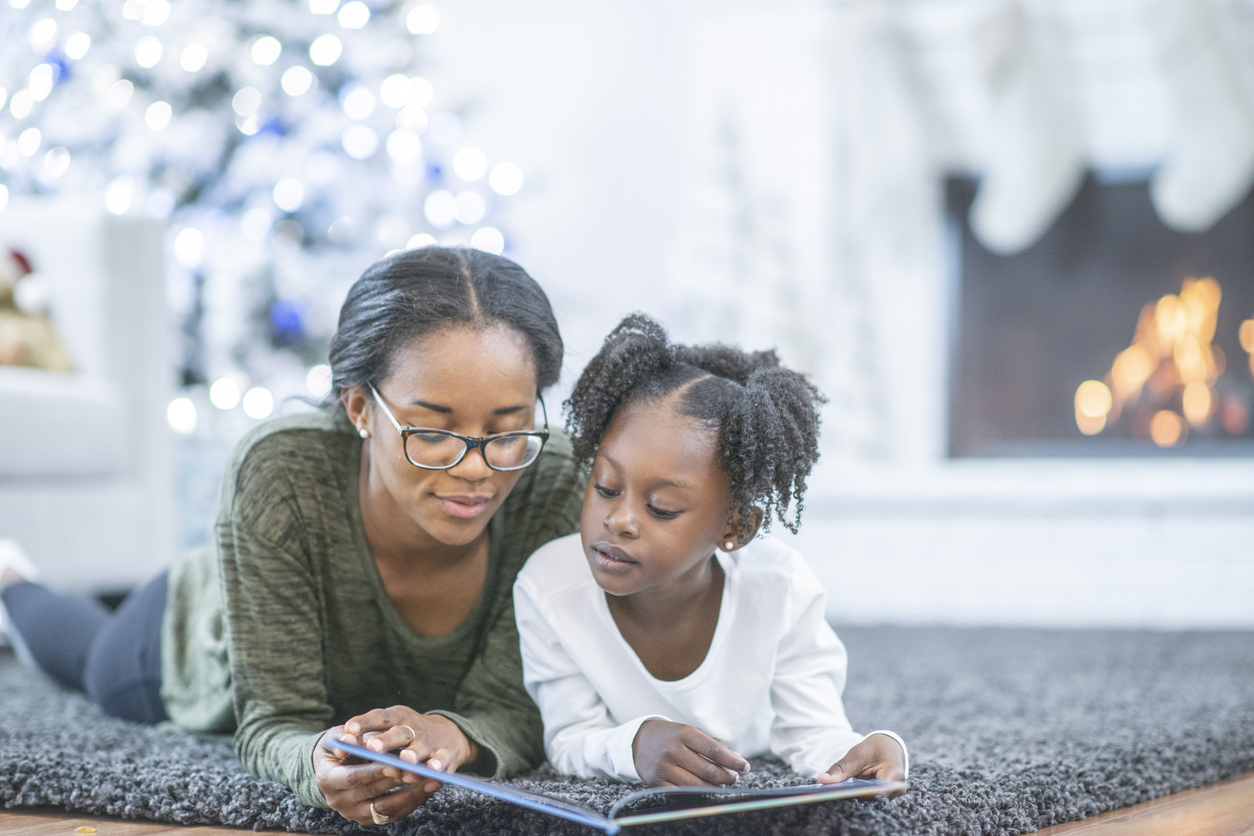 Little girl reading with her mom