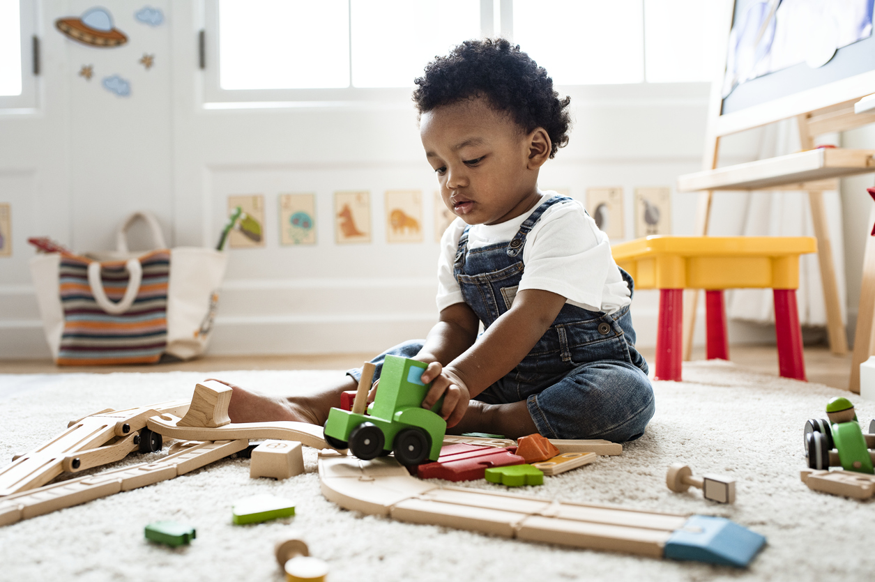 Cute little boy playing with a railroad train toy