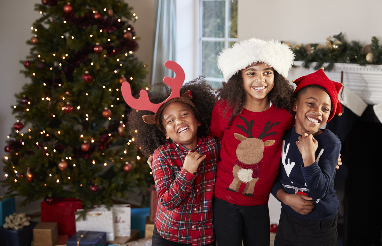 Portrait Of Children Wearing Festive Jumpers And Hats Celebrating Christmas At Home Together