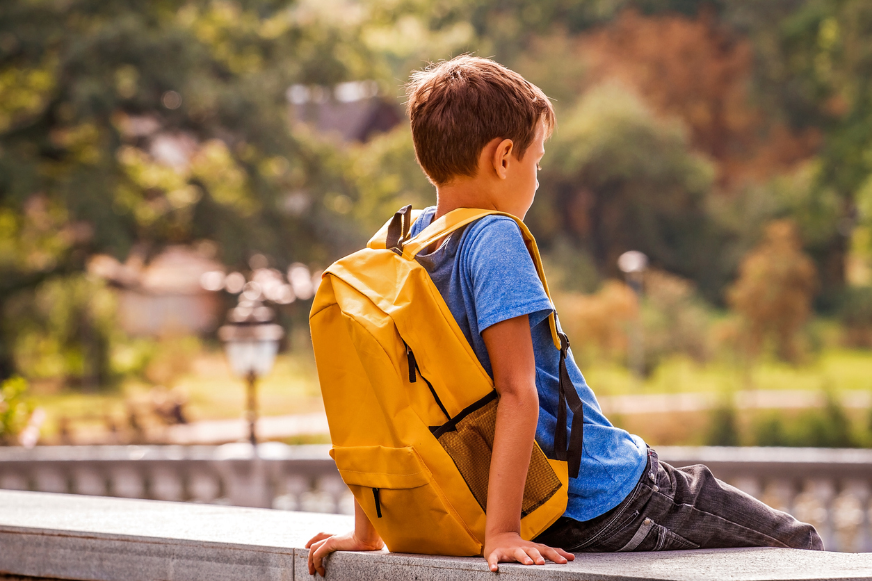 Sad alone boy sitting in the park outdoors