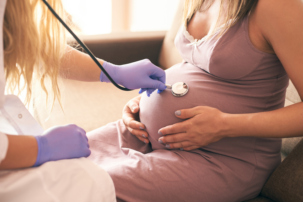 View from side of female doctor examining pregnant woman