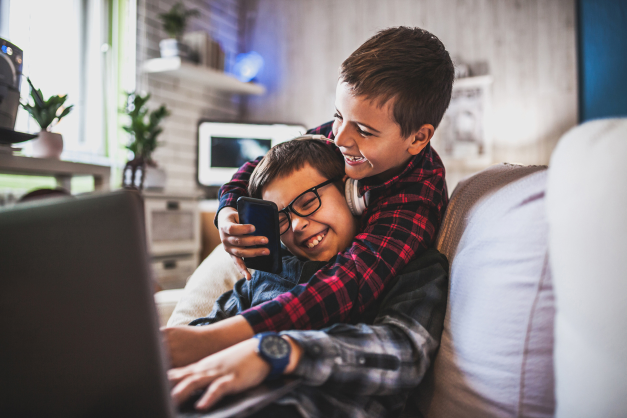 Two teenage boys with gadgets on couch at home