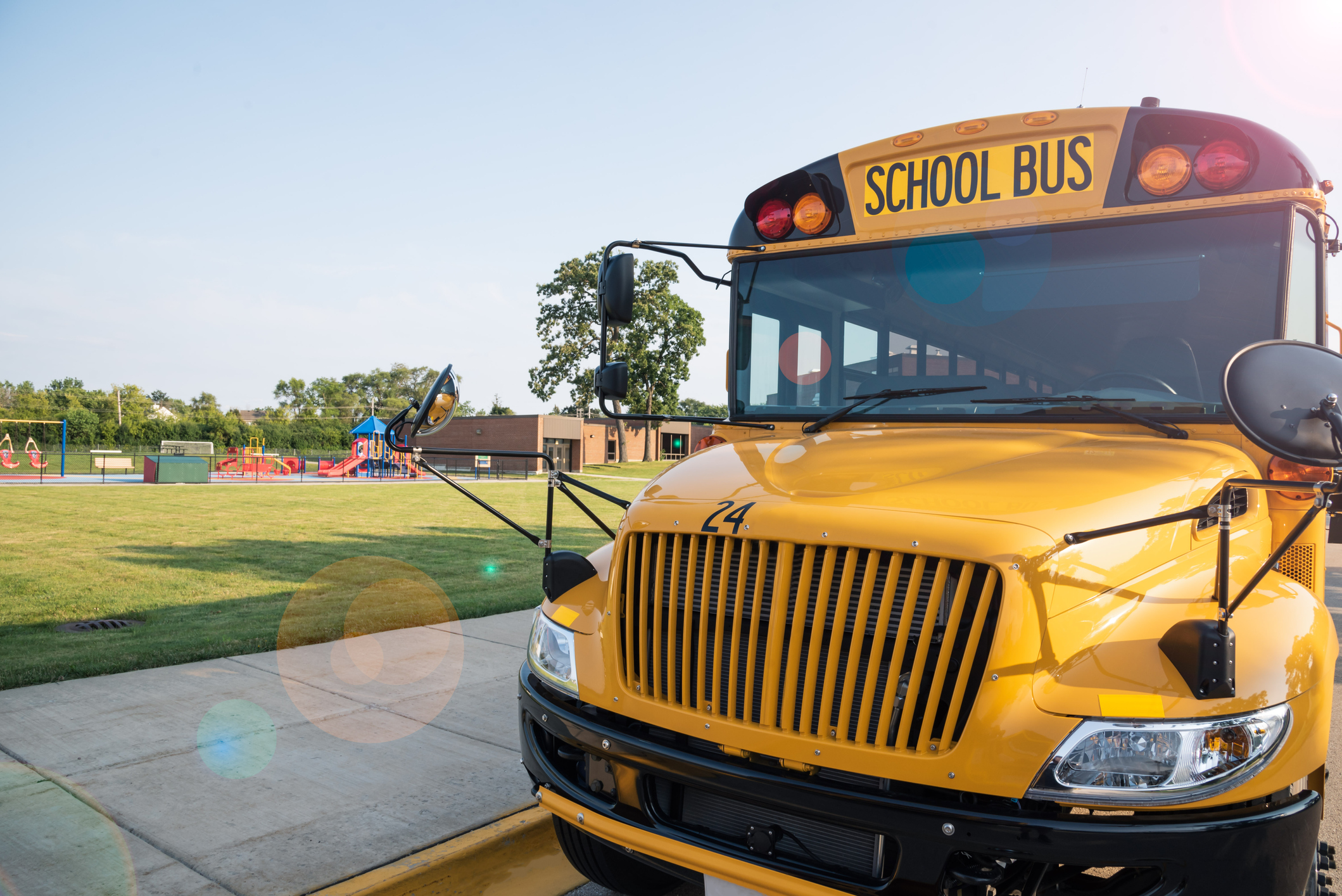 Yellow school bus parked next to playground