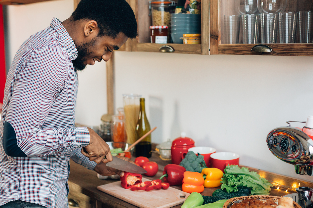 African-american man cutting bell pepper in kitchen