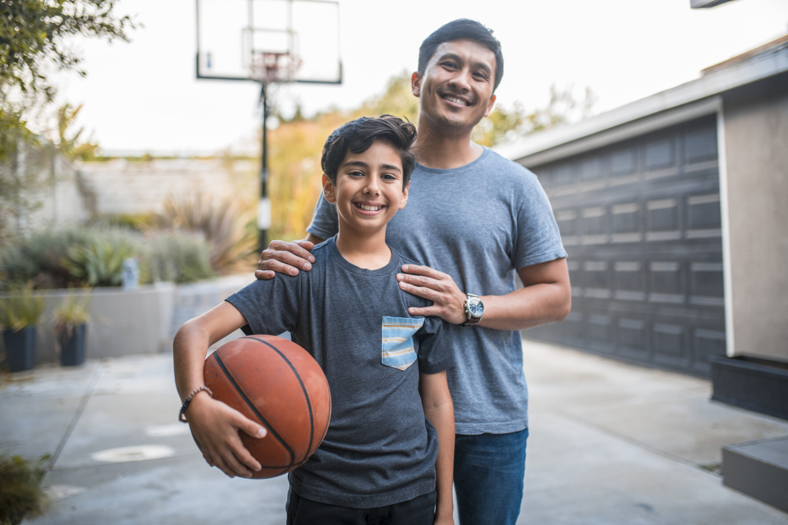 Happy boy and father standing at basketball court