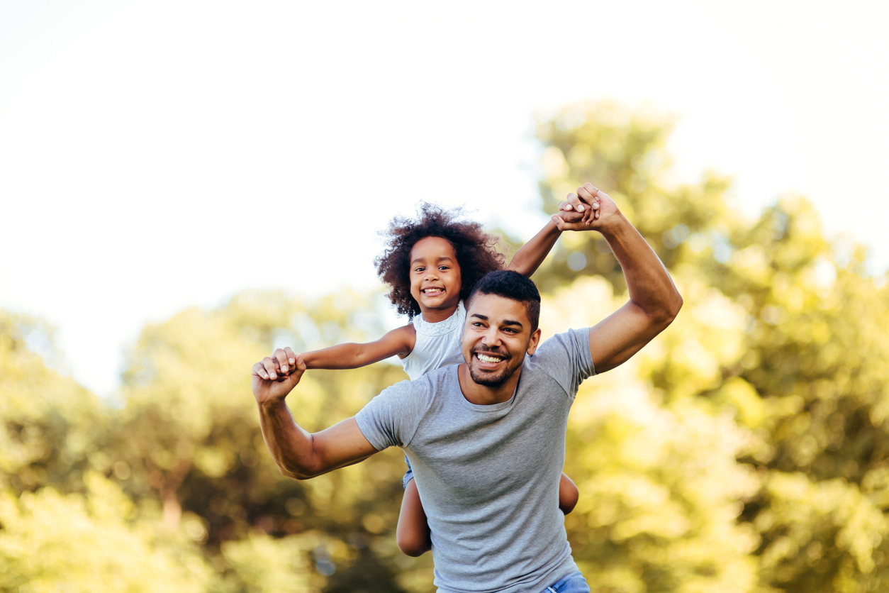 Portrait of young father carrying his daughter on his back