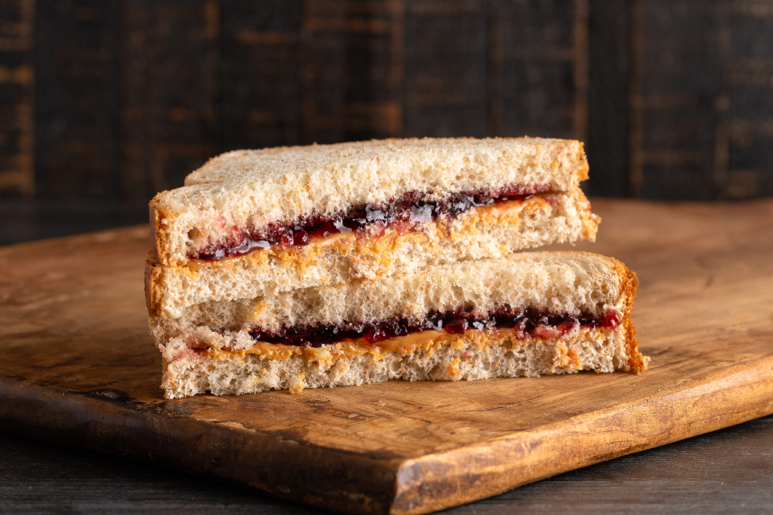 A Peanut Butter and Grape Jelly Sandwich on a Wooden Cutting Board