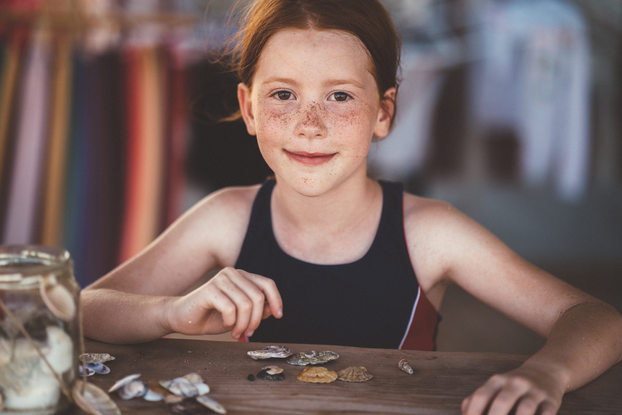 Little girl collecting seashells on seaside vacation