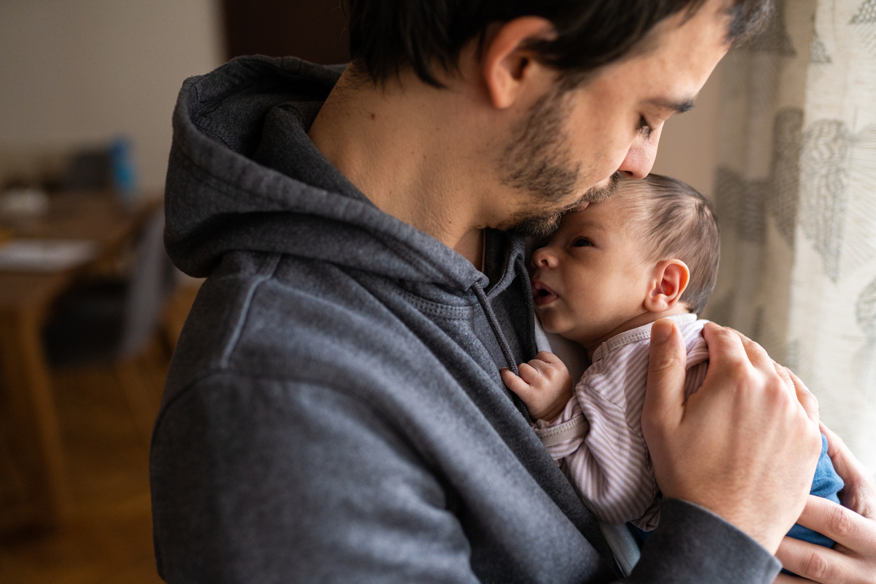 Proud father kissing newborn son