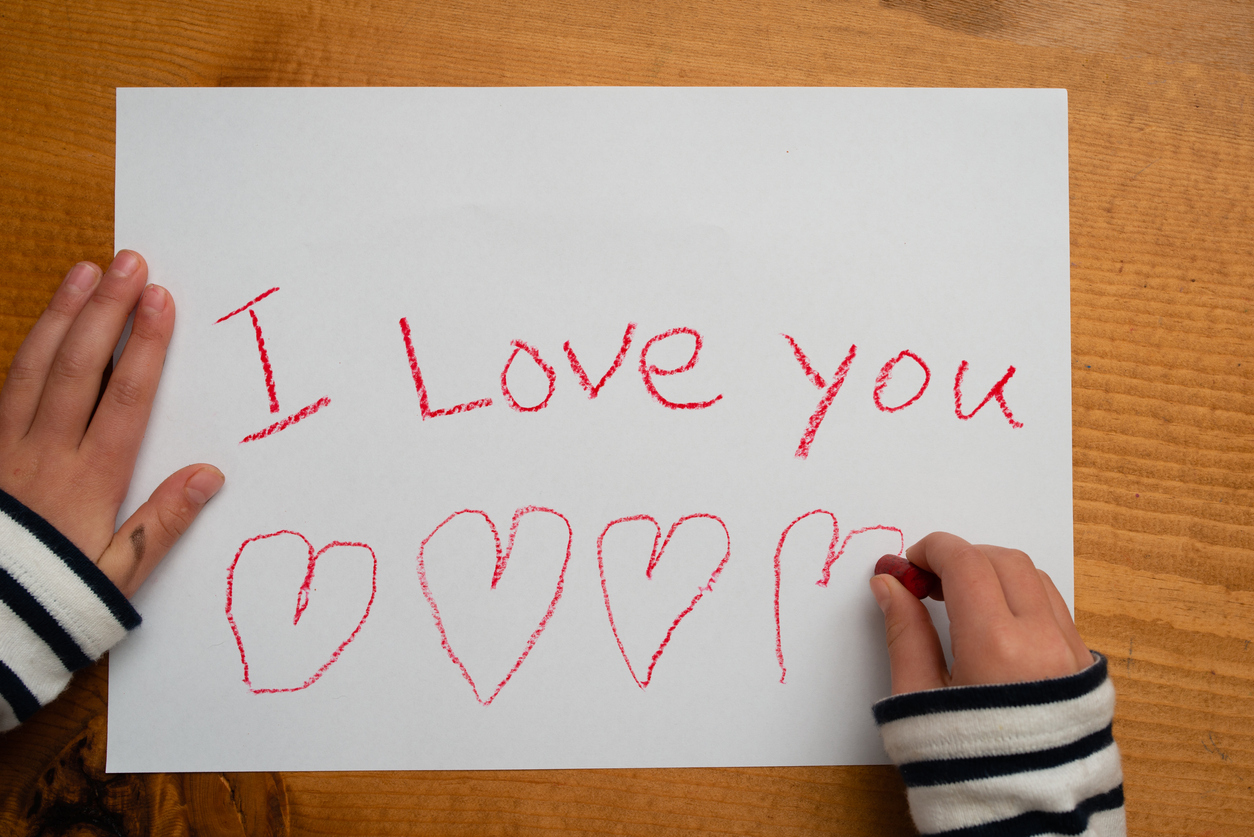 Child writes i love you on paper