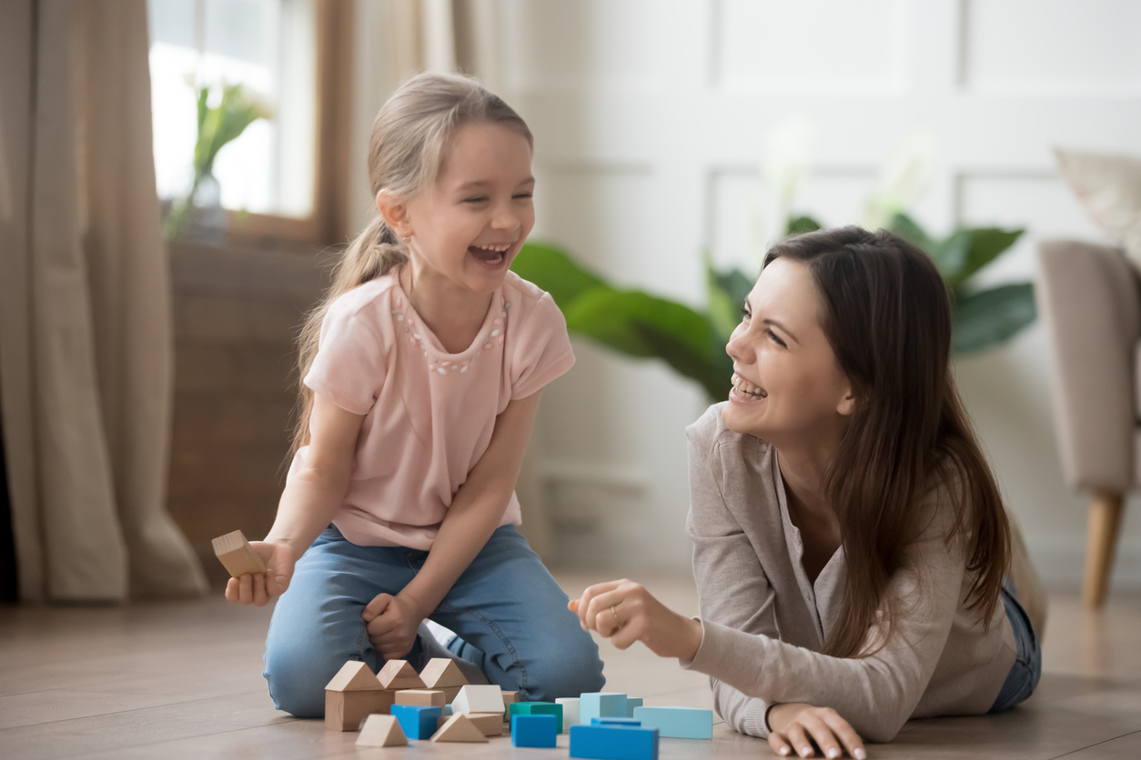 Happy mom and kid daughter laughing playing with wooden blocks