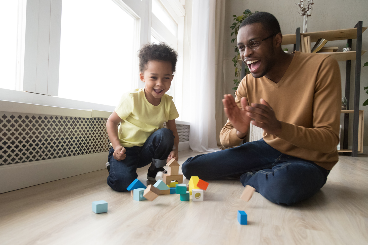 Happy joyful african dad and toddler son laughing playing together