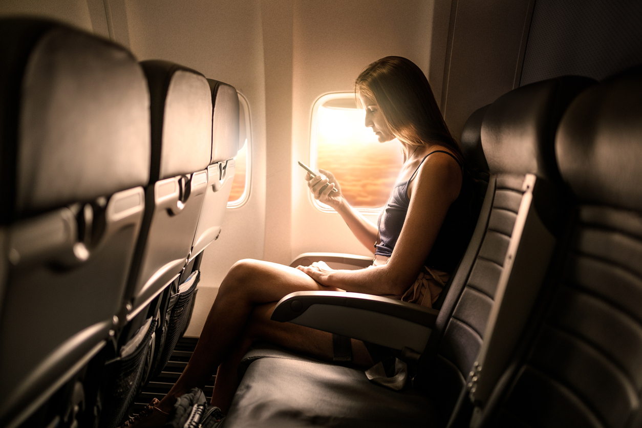 Woman using smartphone in airplane seat