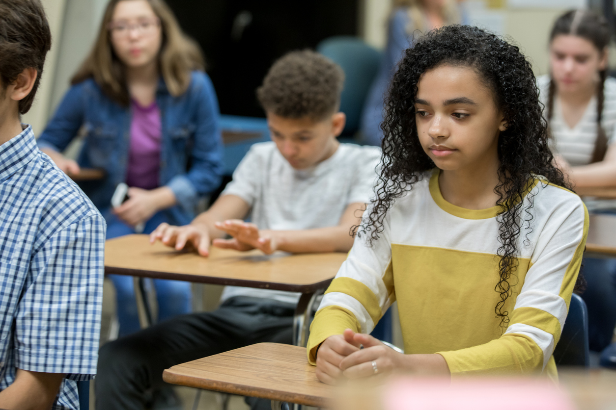 Diverse group of teenage high school students sitting at desks during detention, looking bored and depressed