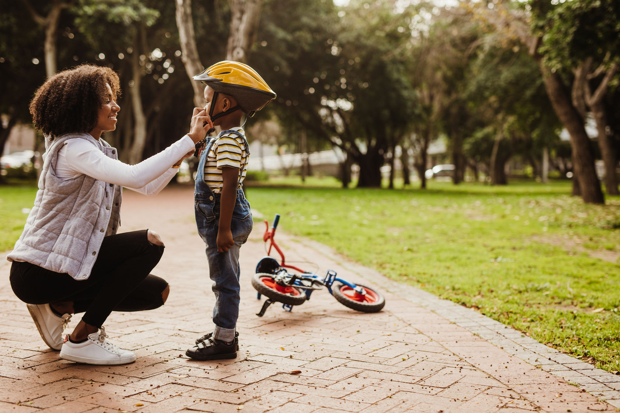 Mother helping son wearing helmet for cycling