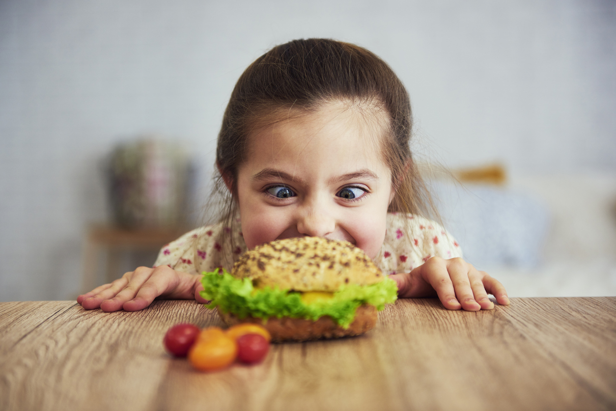 Playful girl looking at delicious hamburger