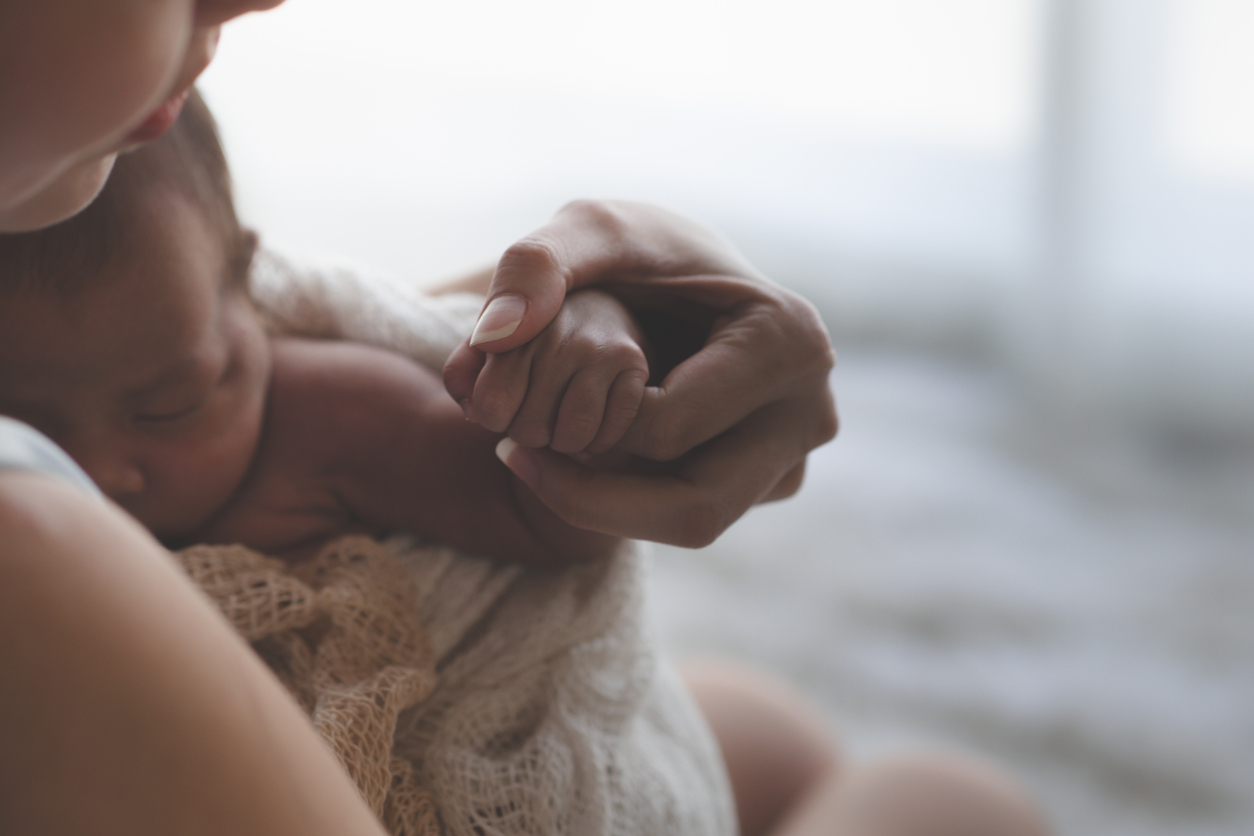 Close up Mother holding hands Asian female newborn baby  and sunlight in the morning. Cute little girl  three weeks old. Health, care, love, relationship concept.