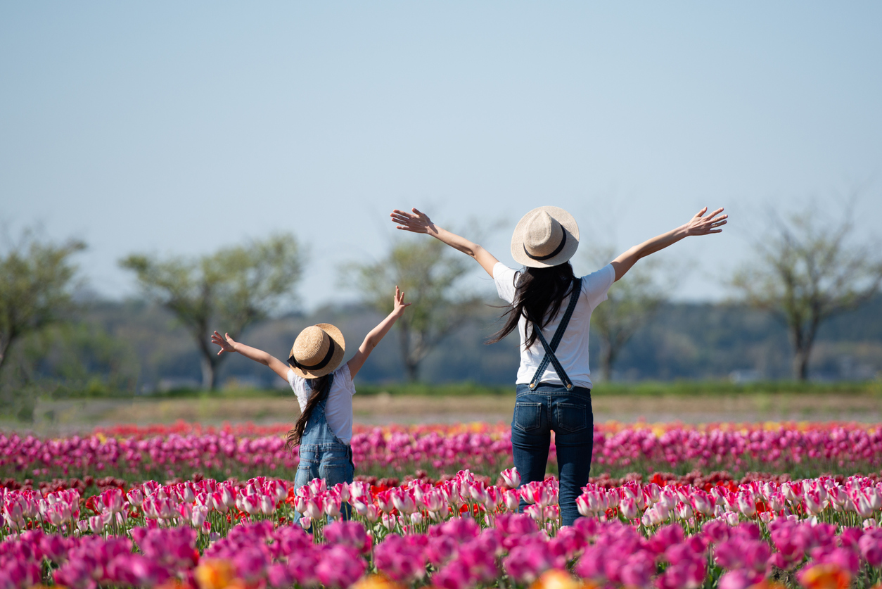 Mother and child raising their hands in the flower field