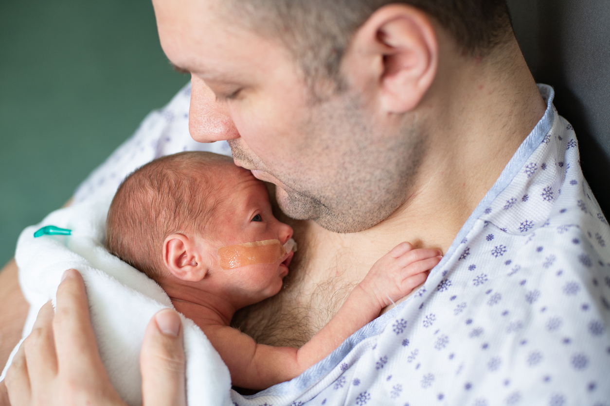 Father taking care of his premature baby doing skin to skin at hospital