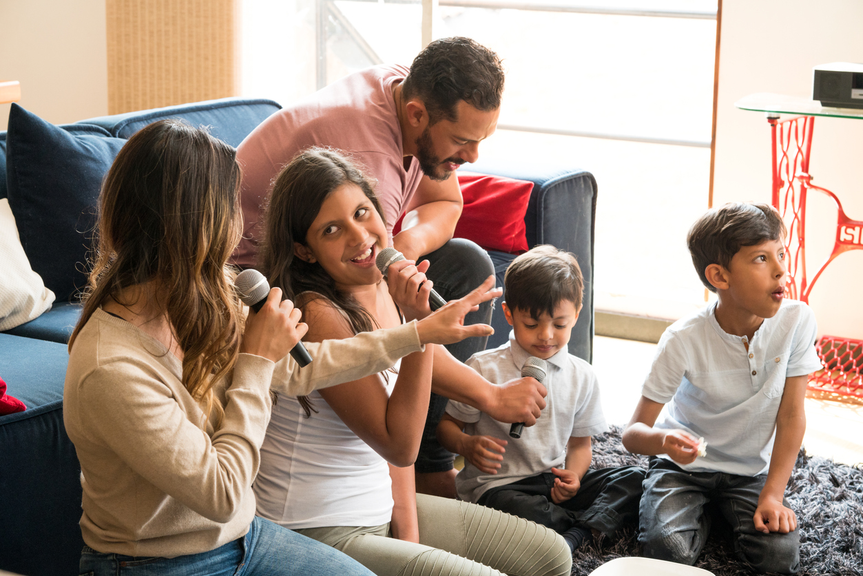 Latin family singing karaoke laughing and enjoying all together in the living room of his house