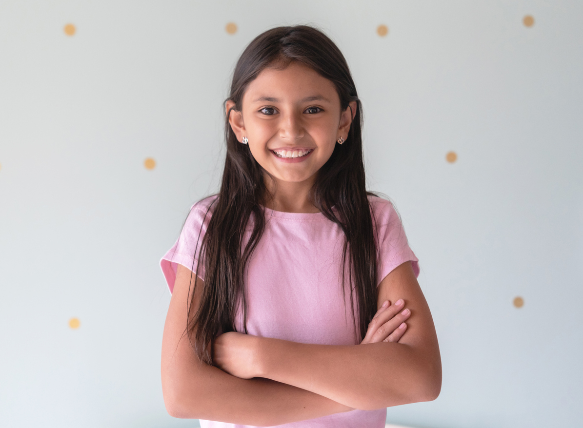 Portrait of beautiful latin american little girl facing camera smiling with arms crossed