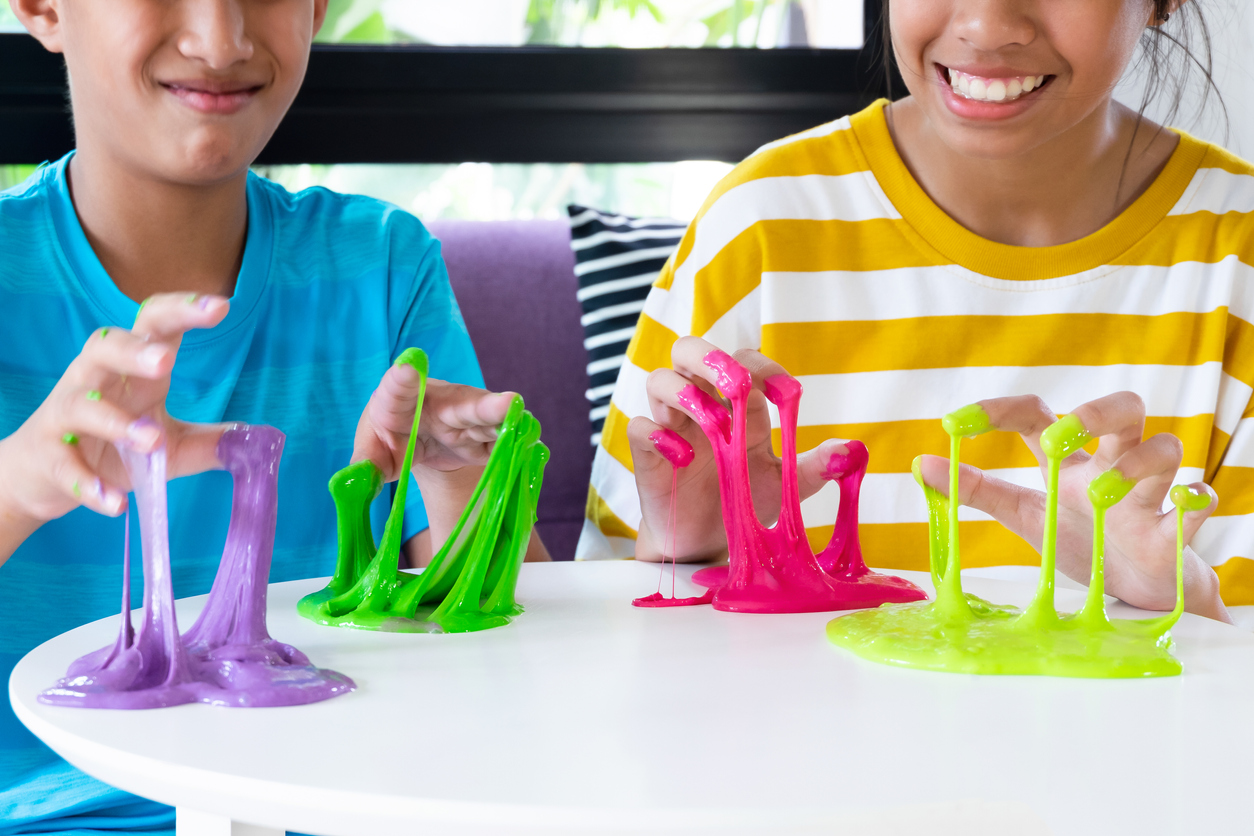 Hand Holding Homemade Toy Called Slime, Sibling boy and girl having fun and being creative by science experiment.