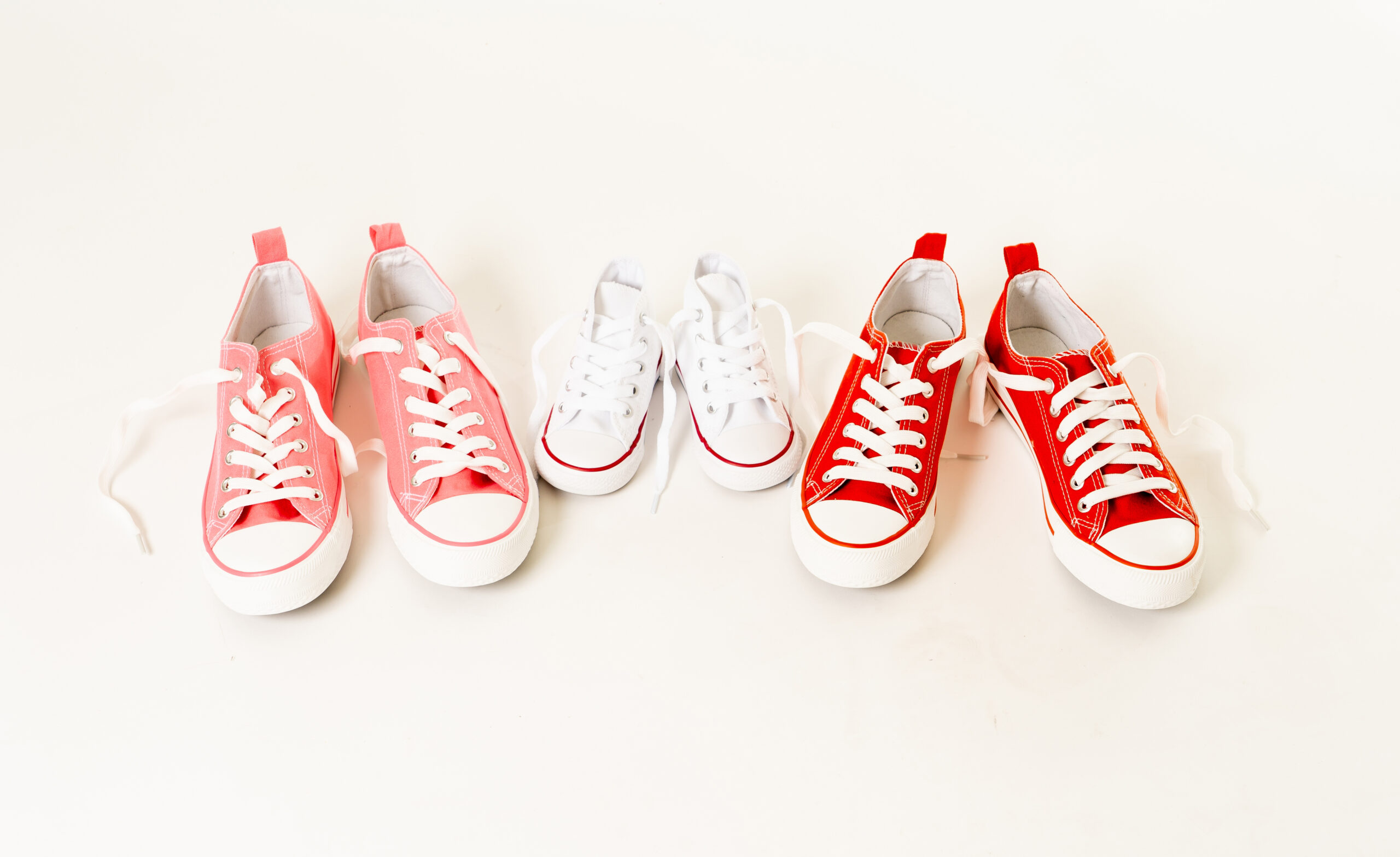 Conceptual image of gumshoes sneakers of two mothers and son daughter isolated on white background copy space in modern family togetherness Parenting styles Education and lifestyle concept.