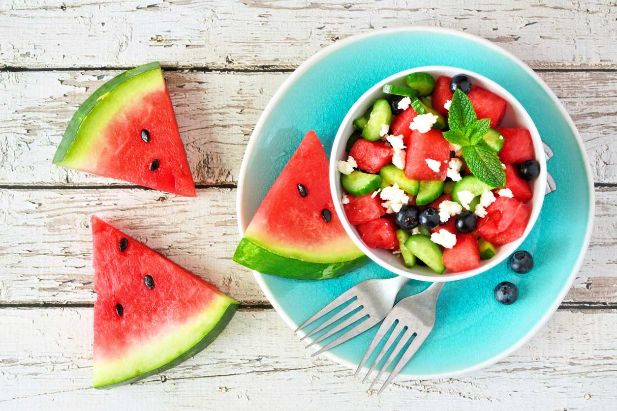 Watermelon salad with cucumber, blueberries and cheese, top view scene on white wood