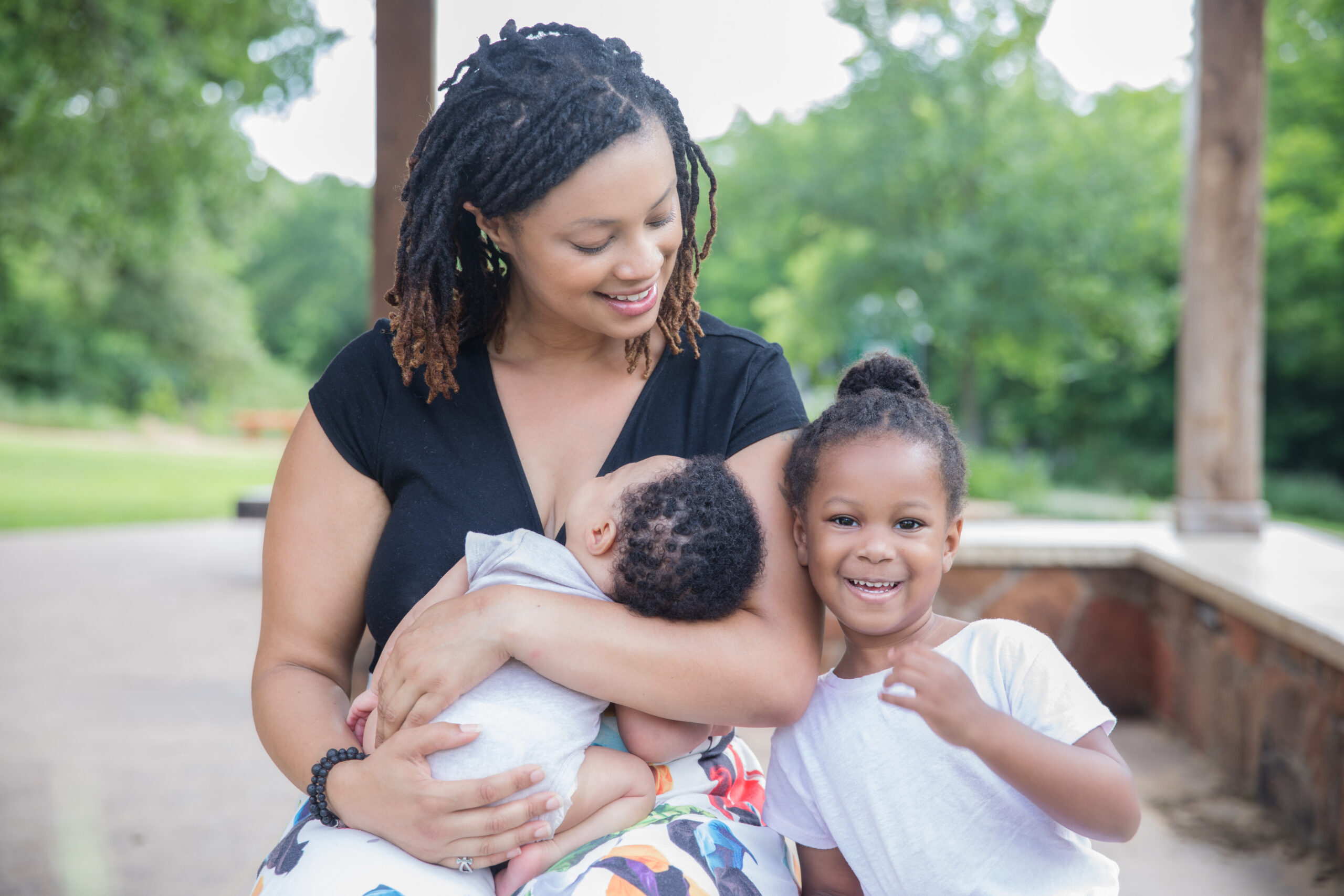 Beautiful little girl smiles while sitting with mother and newborn baby brother