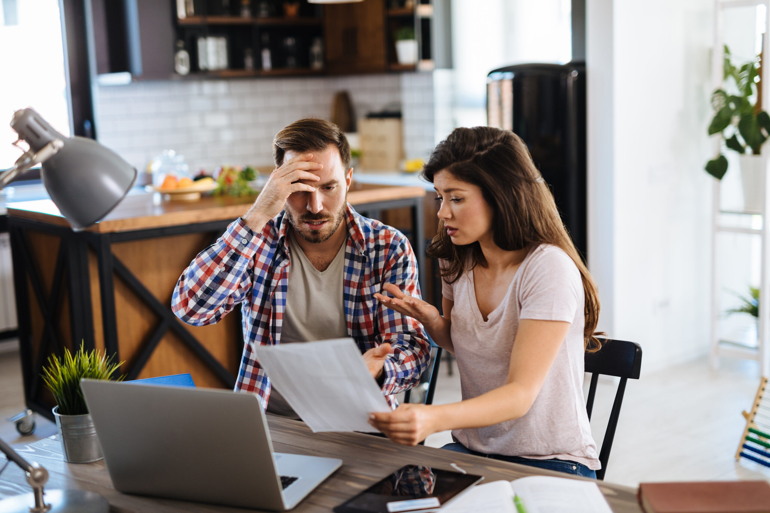 Frustrated couple checking bills at home using laptop