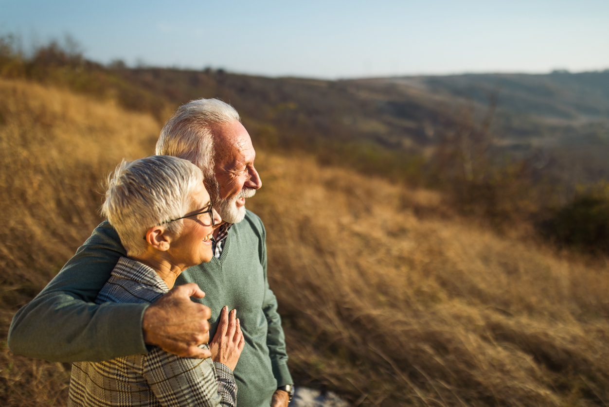 Embraced senior couple enjoying in autumn day on a field.