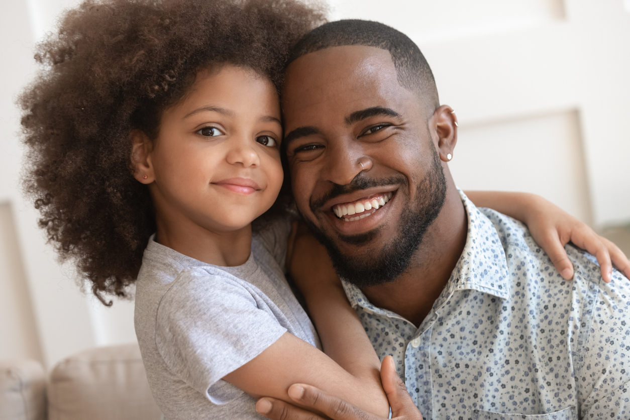 Happy african daddy and small cute child daughter embracing, portrait