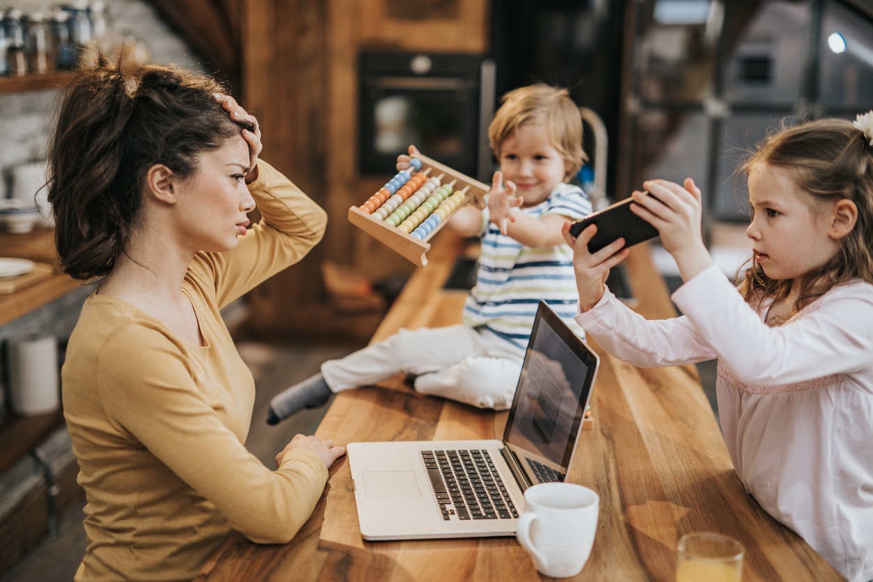 Working single mother feeling frustrated while her kids want to play with her at home.