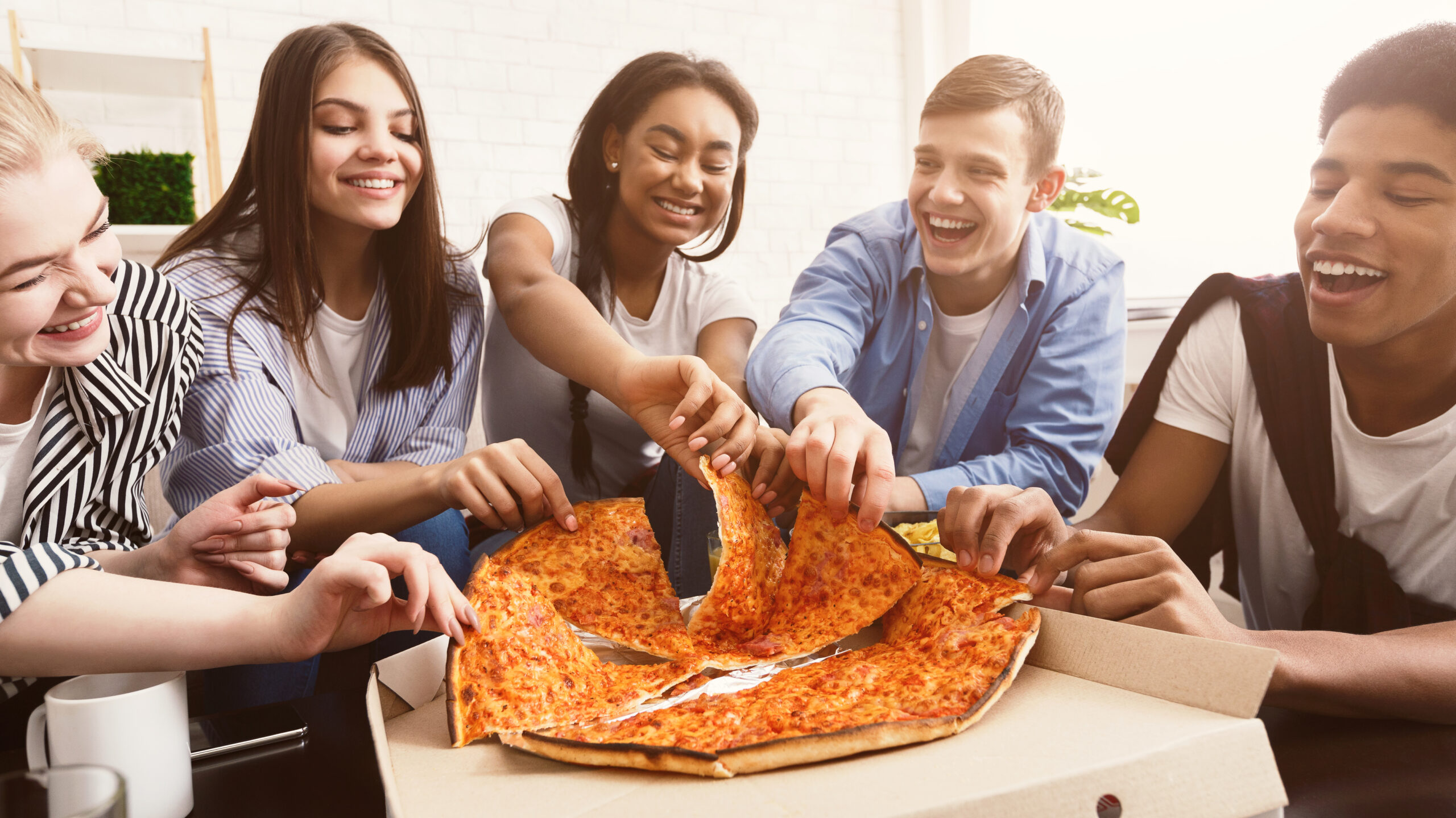 Time for snack. Happy students eating pizza and chatting