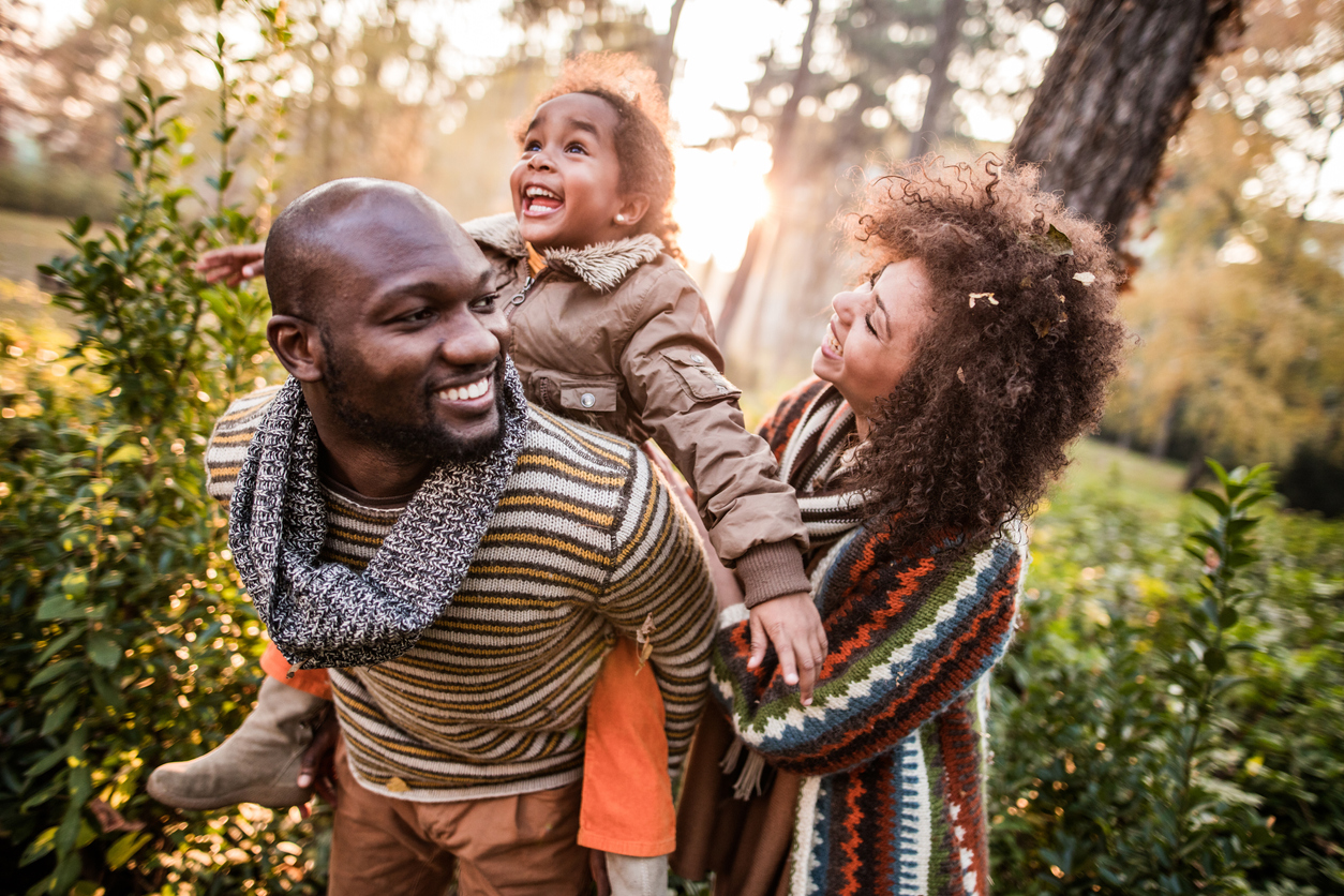 Happy black parents having fun with their daughter at the park.