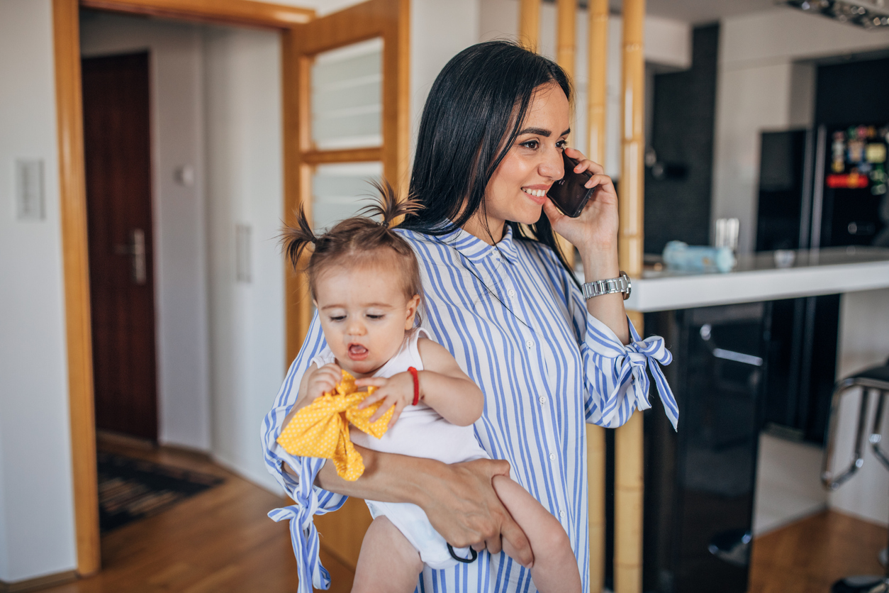 Mom babysitting and talking on mobile at home