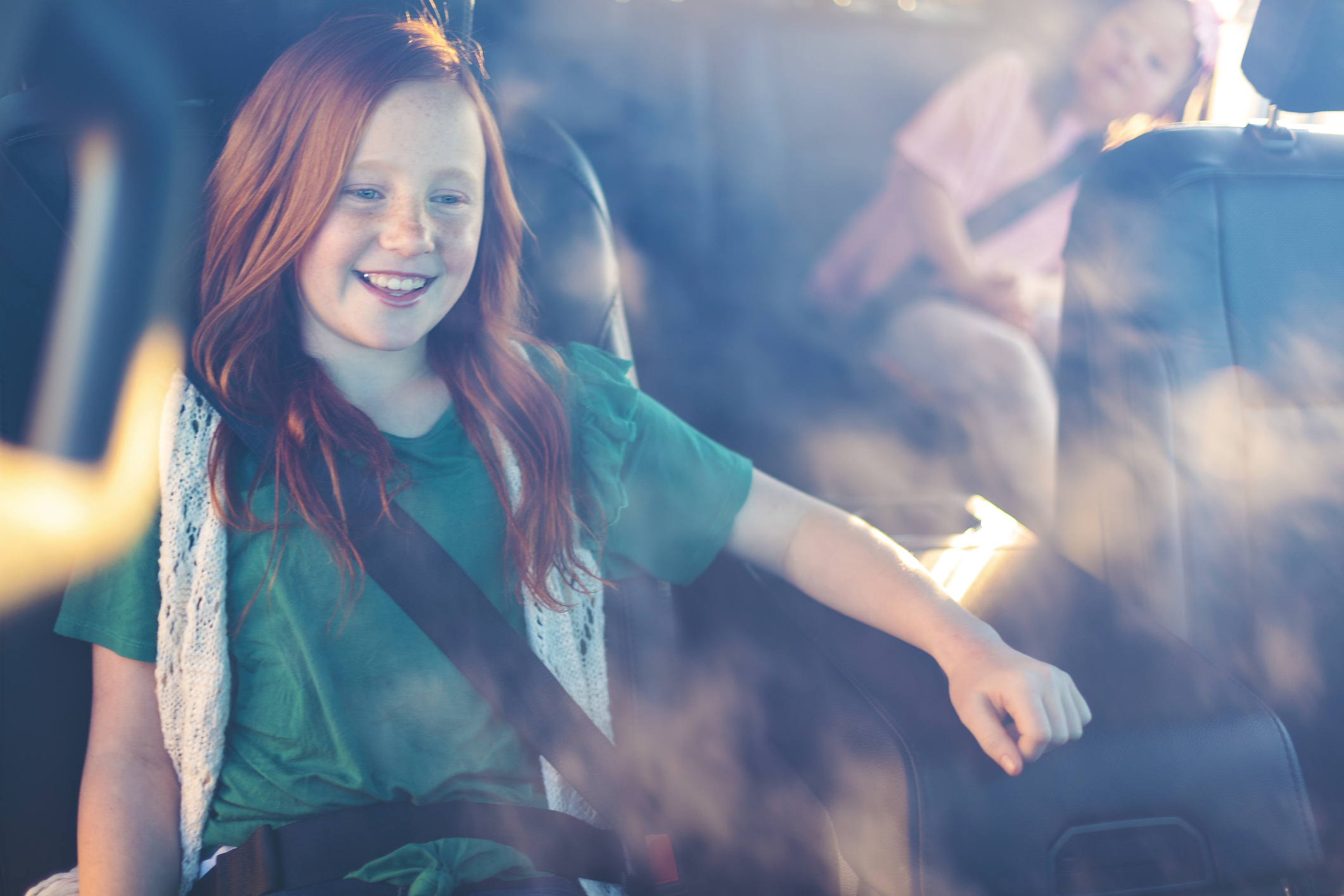 Young Females strapped in safety belts in automobile looking at camera