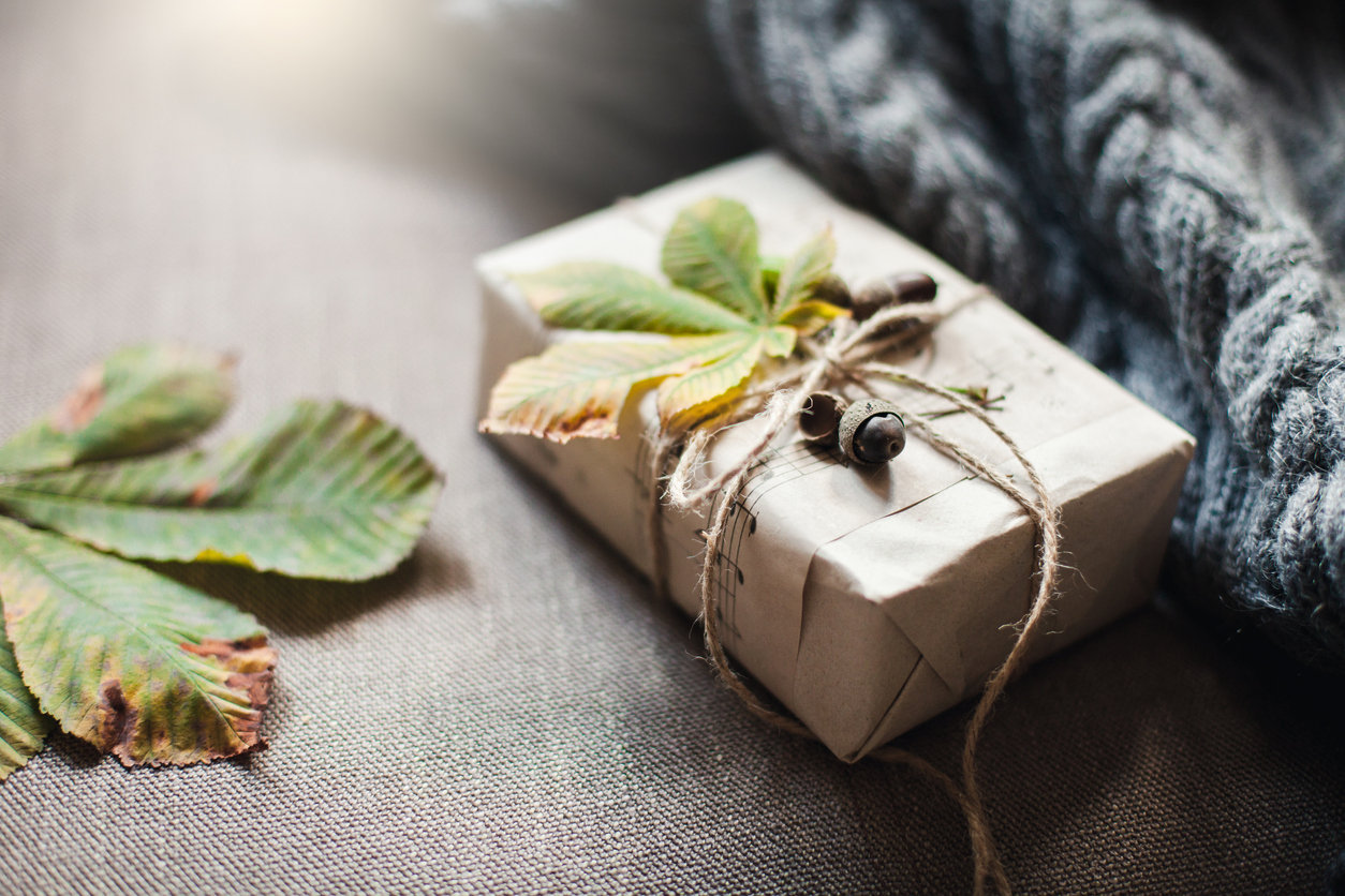 Autumn gifts with fallen leaves. Present for Thanksgiving day is wrapped in kraft paper in rustic style.