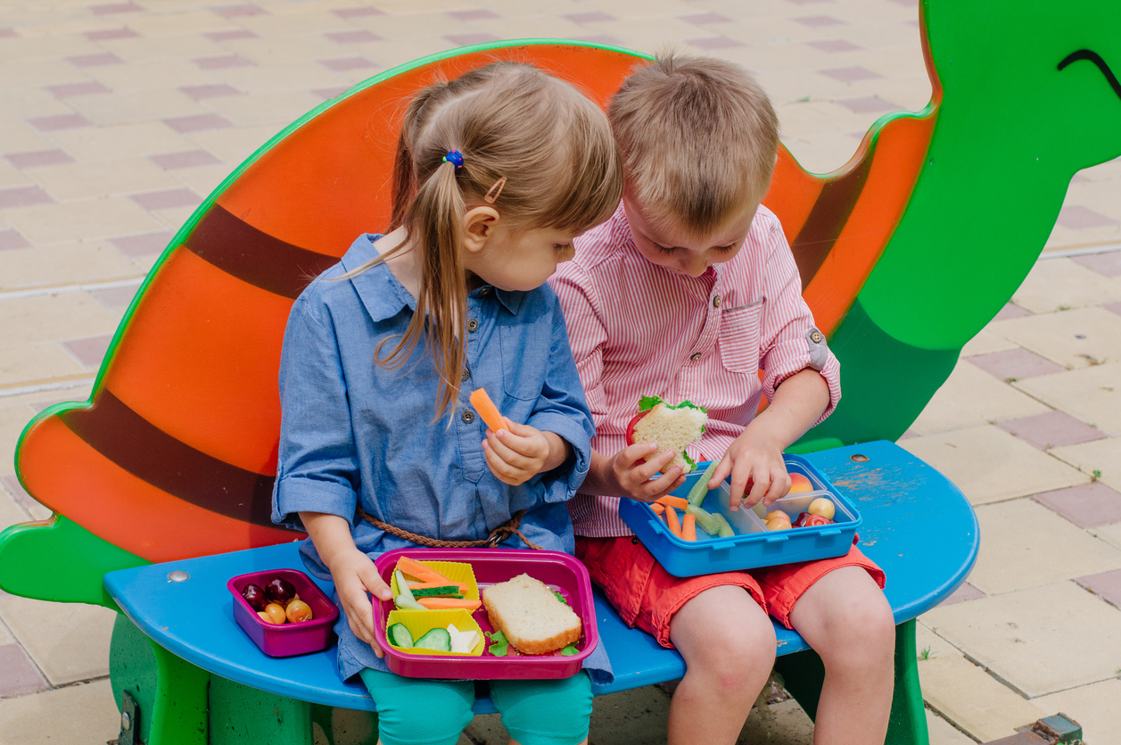 Girl and boy preschool students eating their lunches