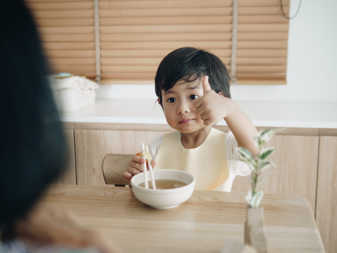 Grandchild eating Udon with grandmother on the table at home.